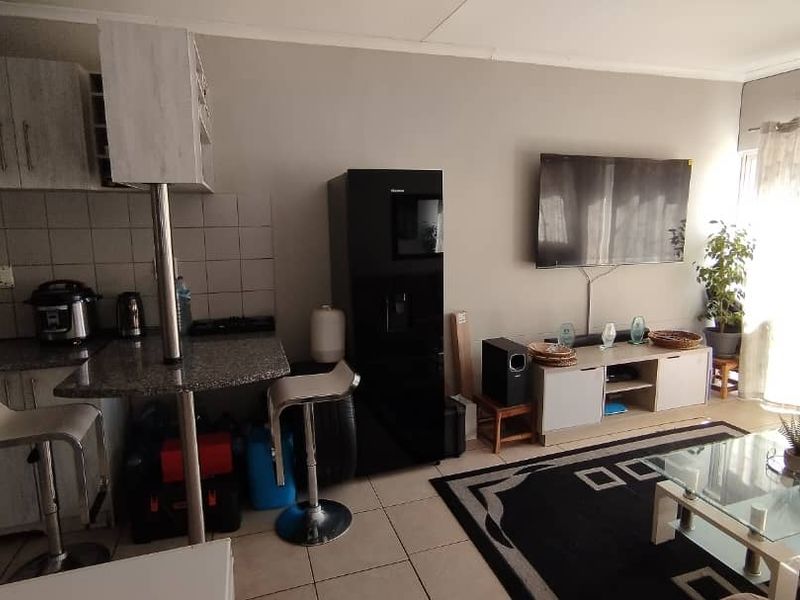 Open-plan living area featuring a compact kitchen with granite countertops, breakfast bar, and tiled flooring, seamlessly flowing into the lounge space.