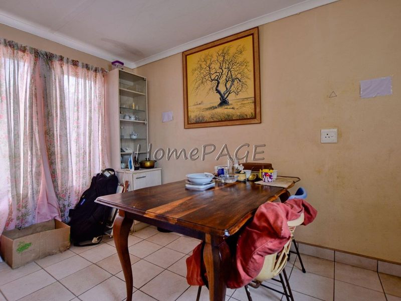 A dining area featuring tiled flooring and coved ceiling cornices, currently showing signs of wear including ceiling water staining and marked wall surfaces.