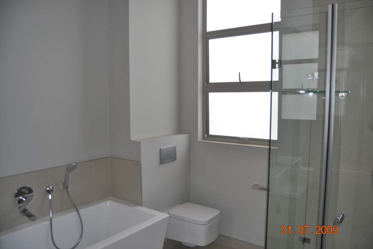 Modern bathroom featuring a built-in bathtub with handheld shower, wall-mounted toilet, and a glass-enclosed shower stall with neutral tiling.