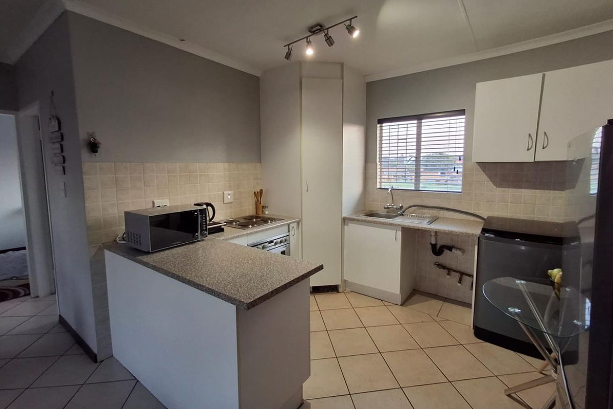 Functional kitchen featuring built-in cabinetry, laminate countertops, tiled backsplash, and integrated oven and hob, with tiled flooring throughout.