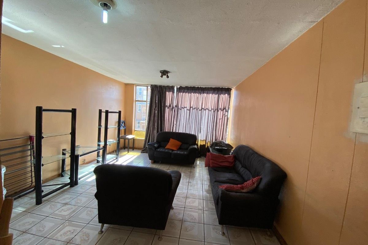 A living room featuring tiled flooring and basic ceiling lighting, offering a blank canvas for potential cosmetic updates and modernization.