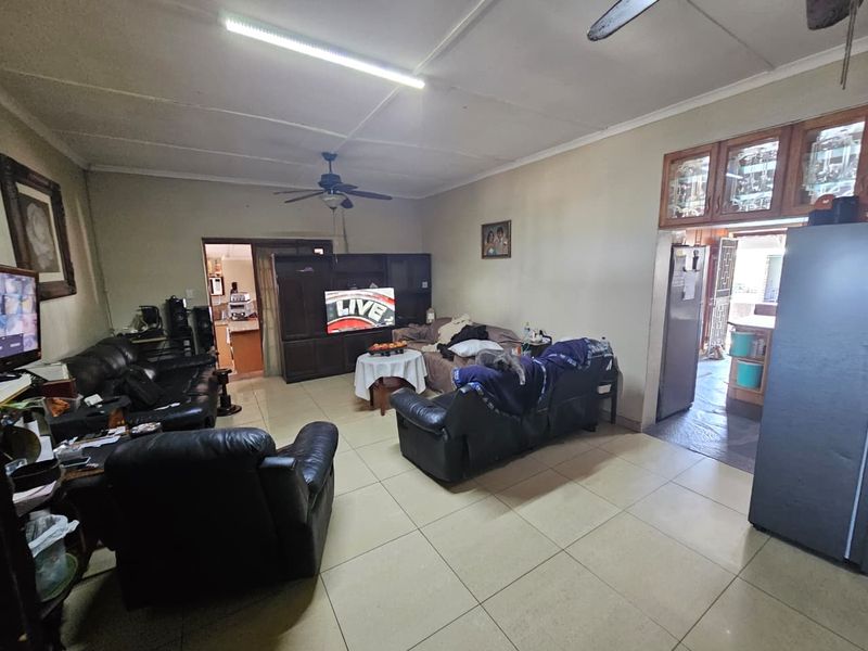 Spacious living room featuring tiled flooring, ceiling fans, and built-in cabinetry, offering a functional layout with potential for modernization.