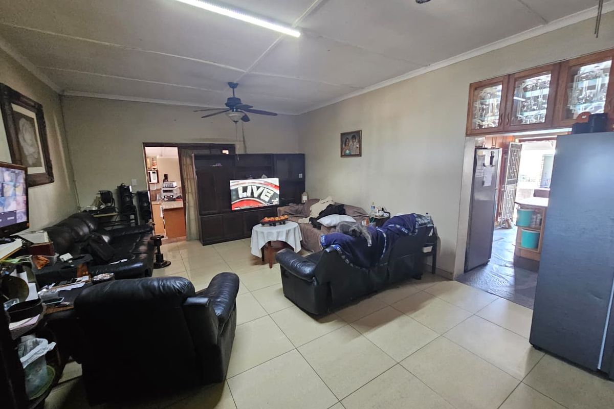 Spacious living room featuring tiled flooring, ceiling fans, and built-in cabinetry, offering a functional layout with potential for modernization.