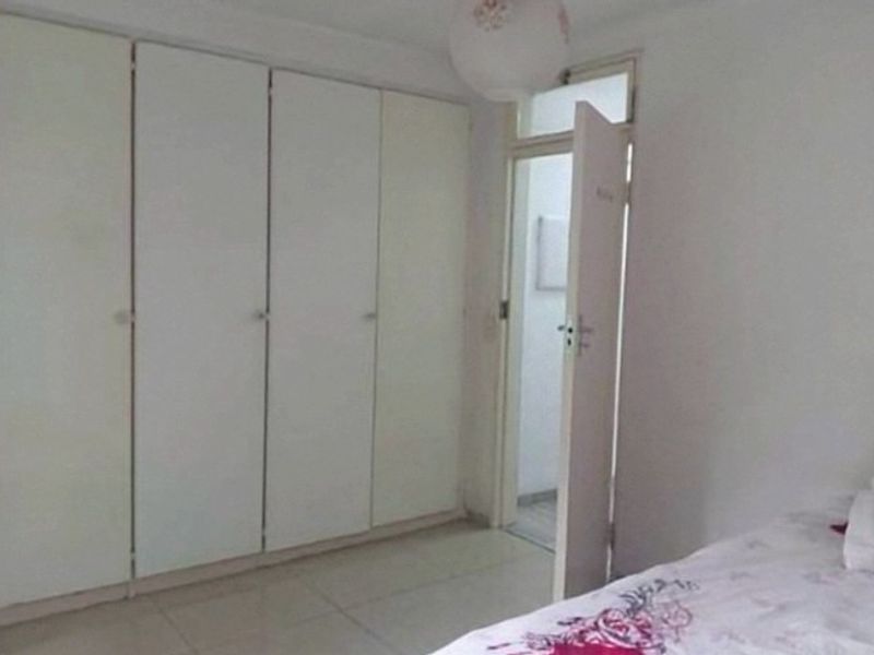 A bedroom featuring built-in cupboards and tiled flooring, with an internal door leading to an adjacent space.