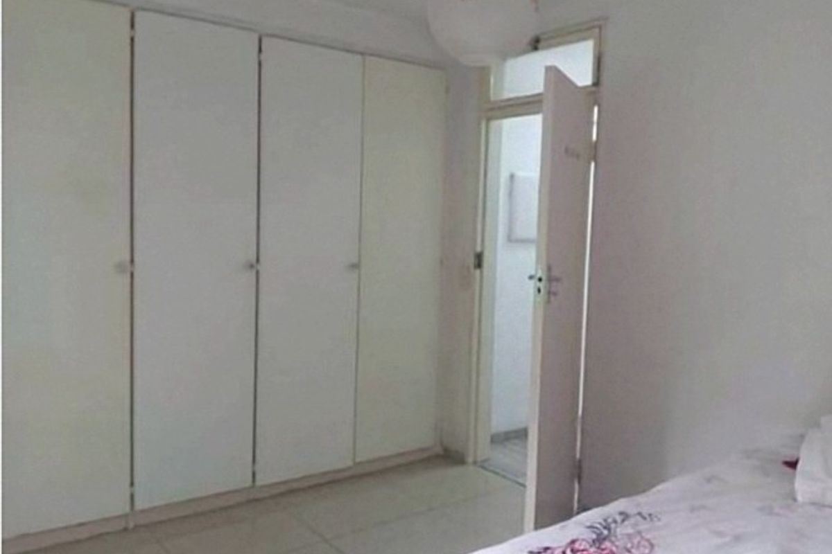 A bedroom featuring built-in cupboards and tiled flooring, with an internal door leading to an adjacent space.