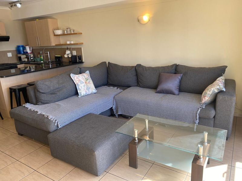 Open-plan living area featuring tiled flooring and a compact kitchen with granite countertops and built-in cabinetry.