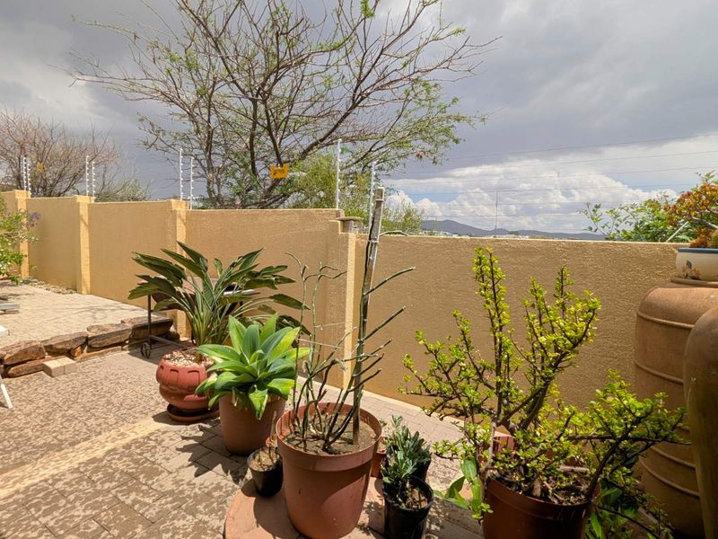 A paved outdoor patio area featuring a boundary wall with integrated electric fencing, offering a private space for outdoor relaxation.