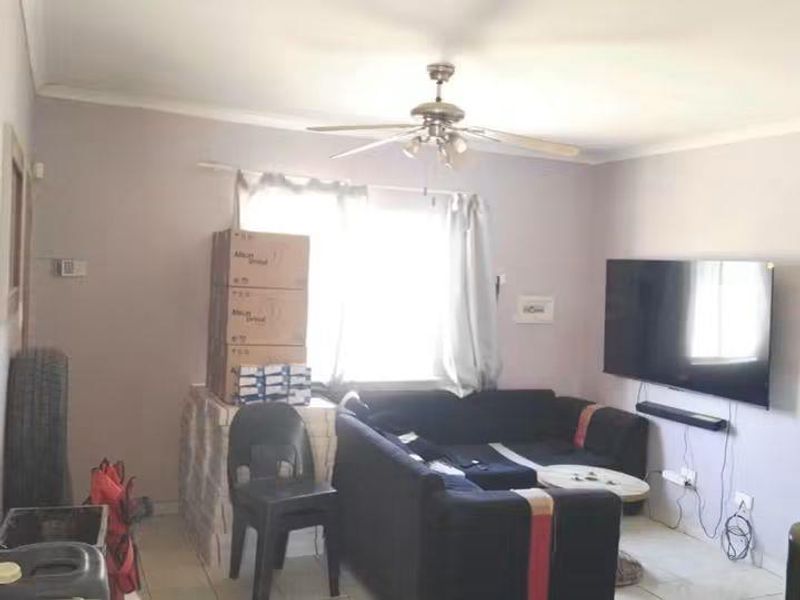 A living room featuring tiled flooring, a ceiling fan, and coved cornicing, providing a functional space for relaxation.