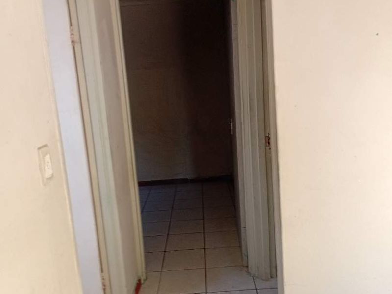 A vacant hallway featuring tiled flooring and neutral wall finishes, requiring minor cosmetic updates to improve its overall presentation.