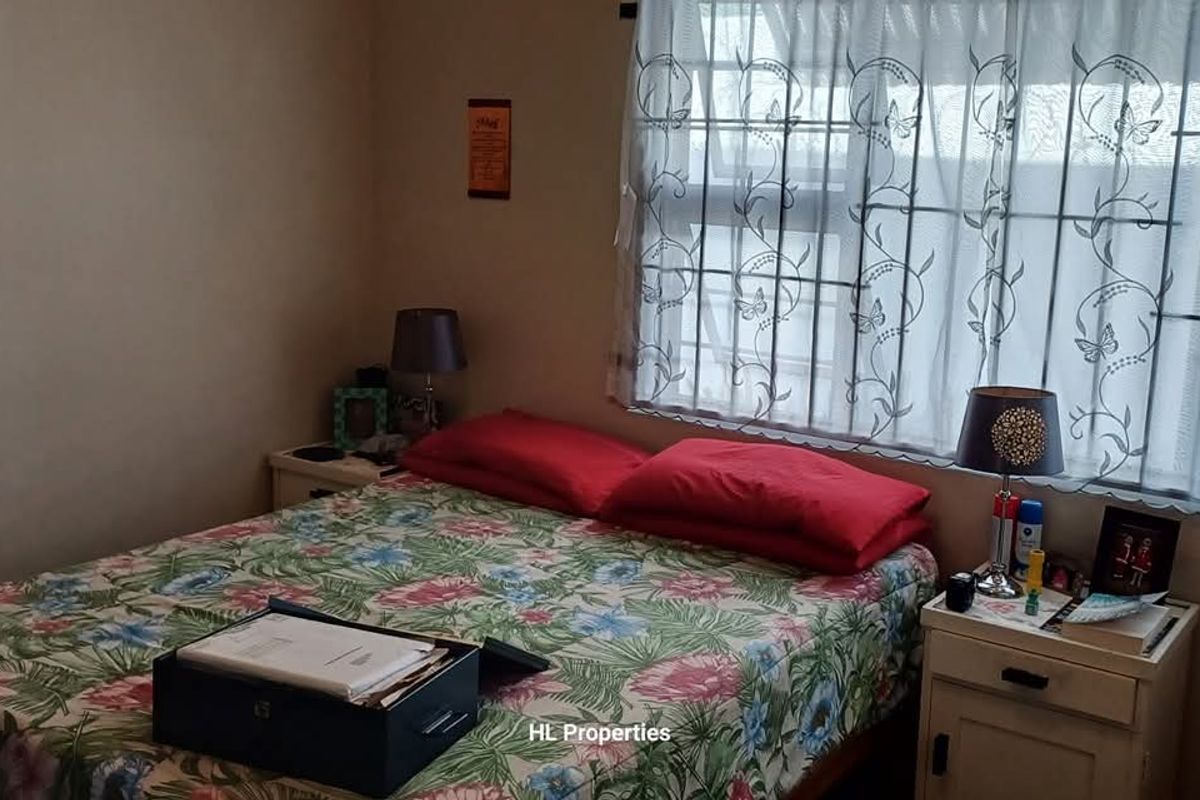 A functional bedroom featuring a window with security bars and neutral wall finishes, providing a comfortable space for rest.