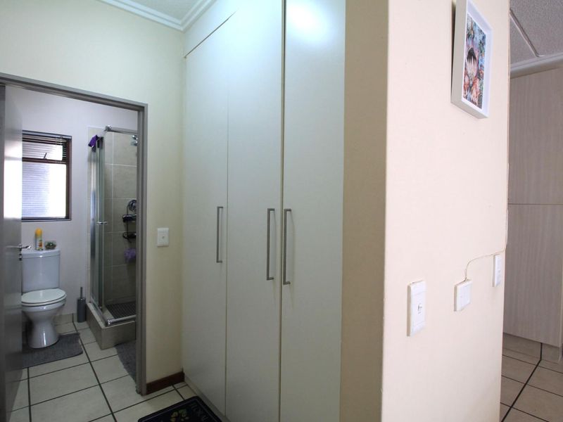 A functional hallway featuring built-in storage cupboards and tiled flooring, providing direct access to an adjacent bathroom.