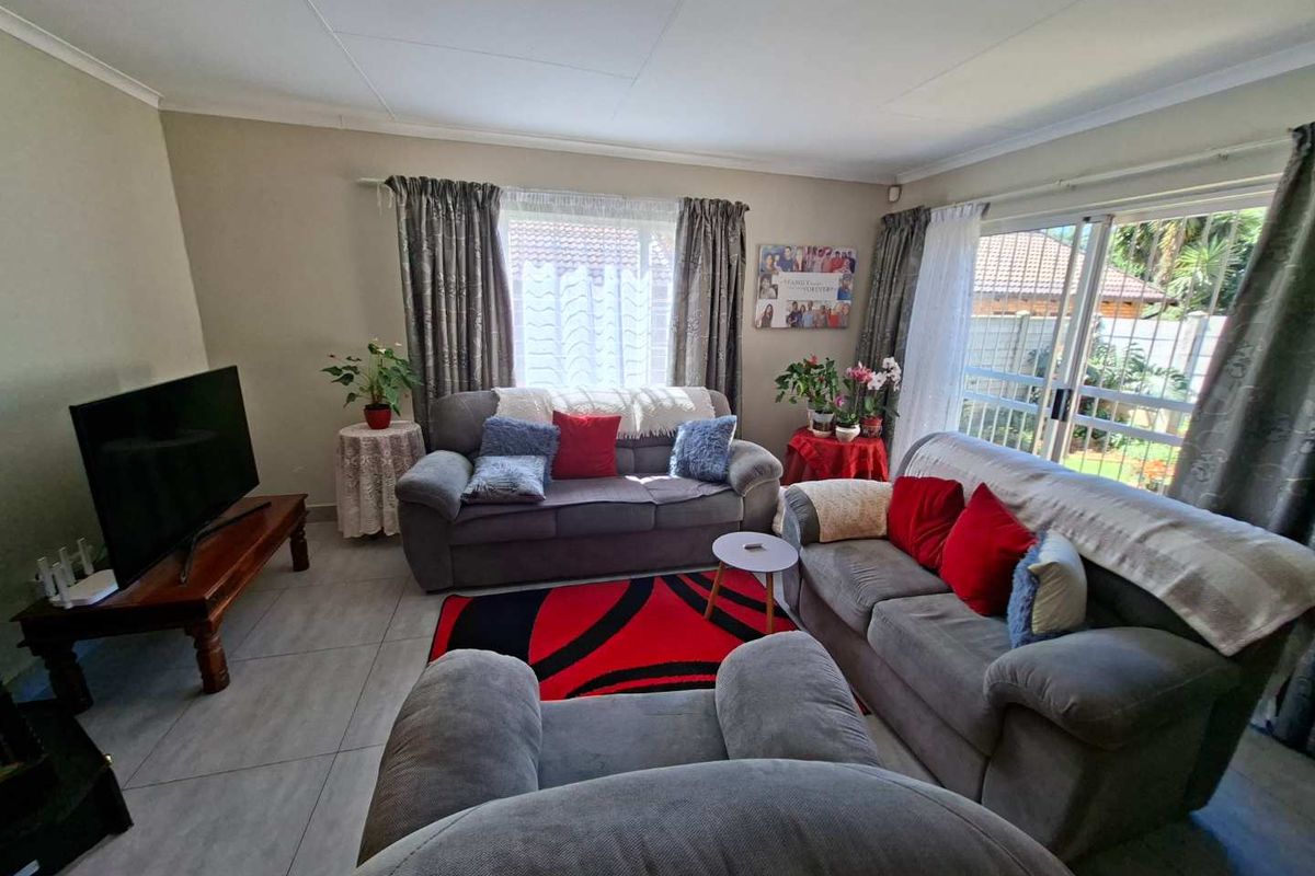 A comfortable living room featuring tiled flooring, neutral wall tones, and a sliding glass door providing access to the outdoor area.
