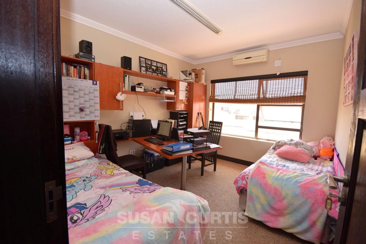 A functional bedroom featuring built-in cabinetry, a desk area, and a wall-mounted air conditioning unit.
