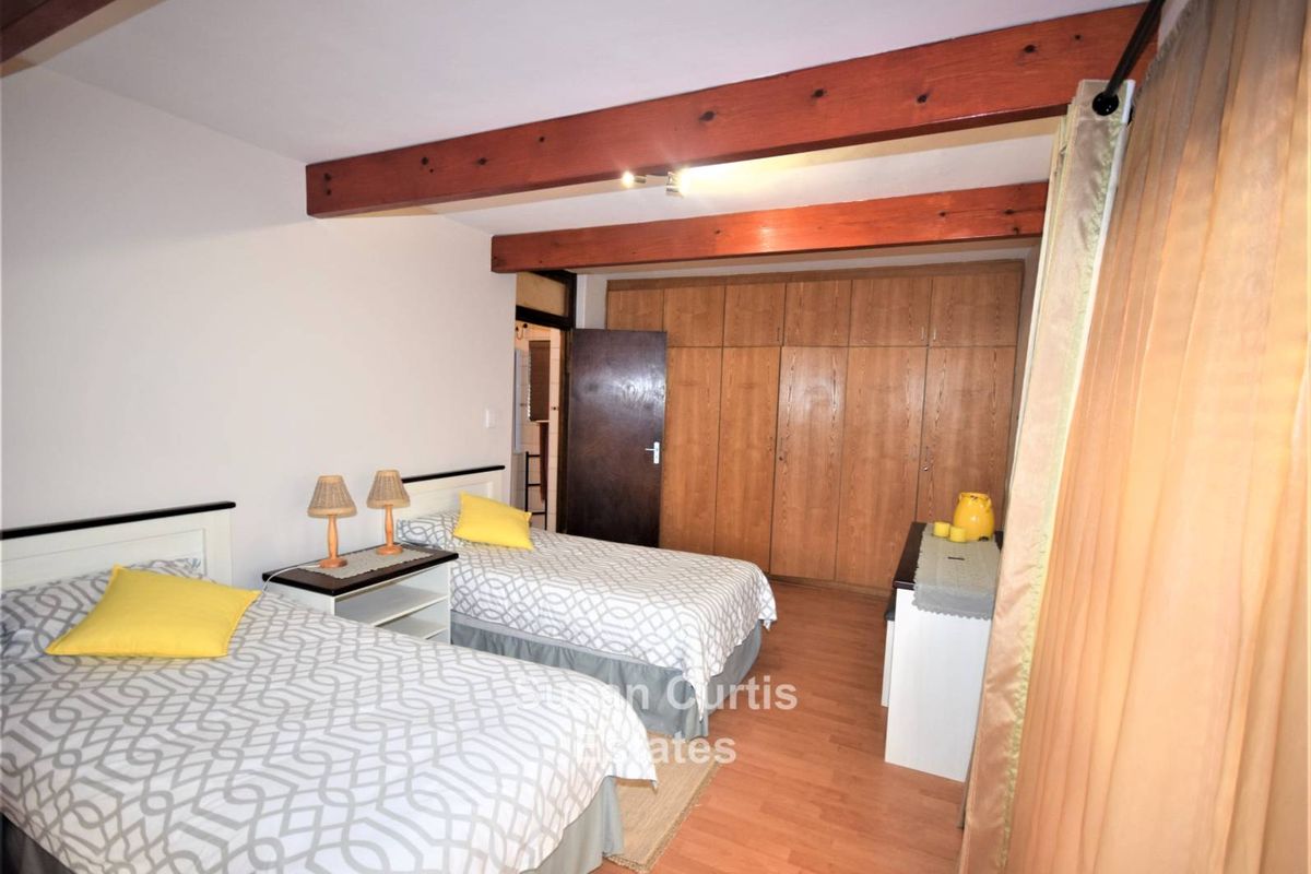 Bedroom featuring exposed timber ceiling beams and built-in wooden cabinetry with laminate flooring.