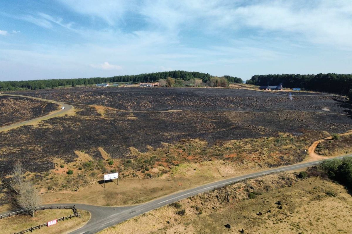 Aerial view of a large plot of land showing extensive fire damage to the vegetation and surrounding rural landscape.
