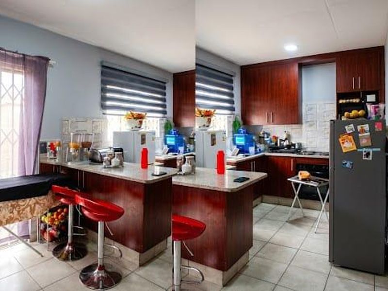 A functional kitchen featuring dark wood cabinetry, granite countertops, built-in oven and hob, and tiled flooring with direct access to an outdoor area.