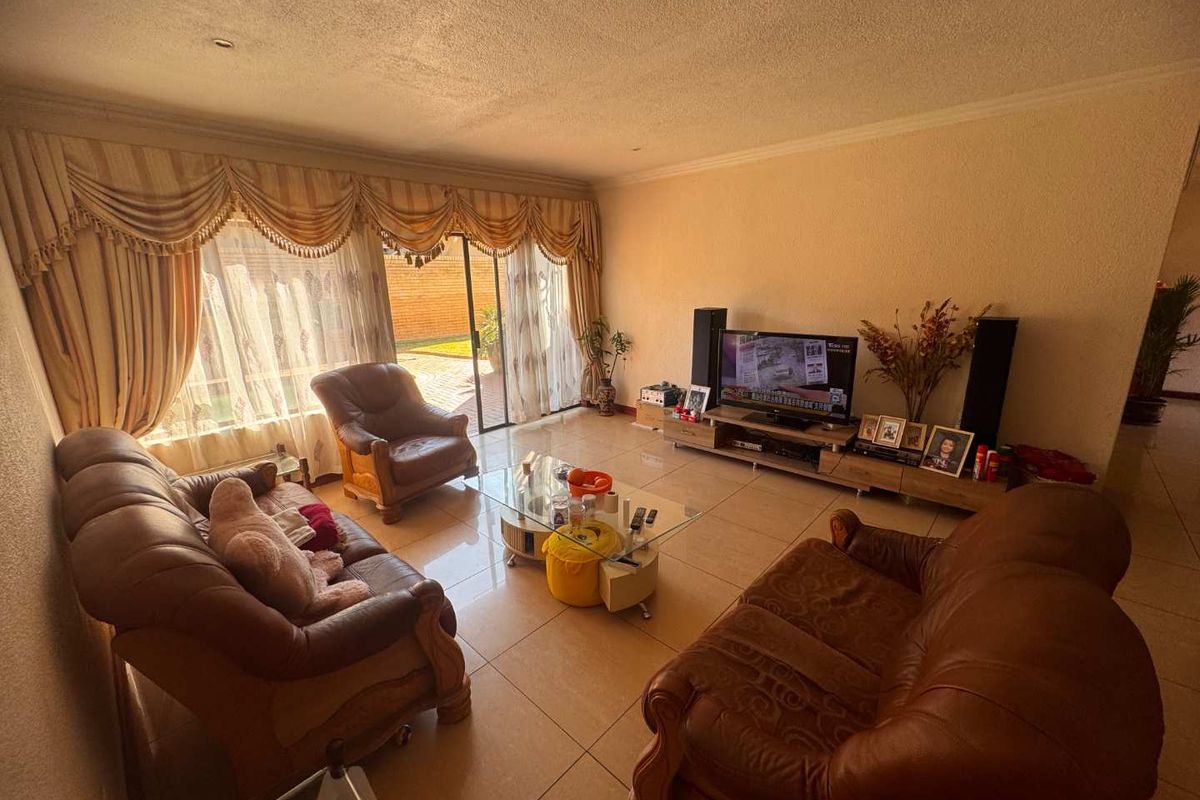 Spacious living room featuring large sliding glass doors providing natural light and access to the outdoor area, finished with neutral tiled flooring.