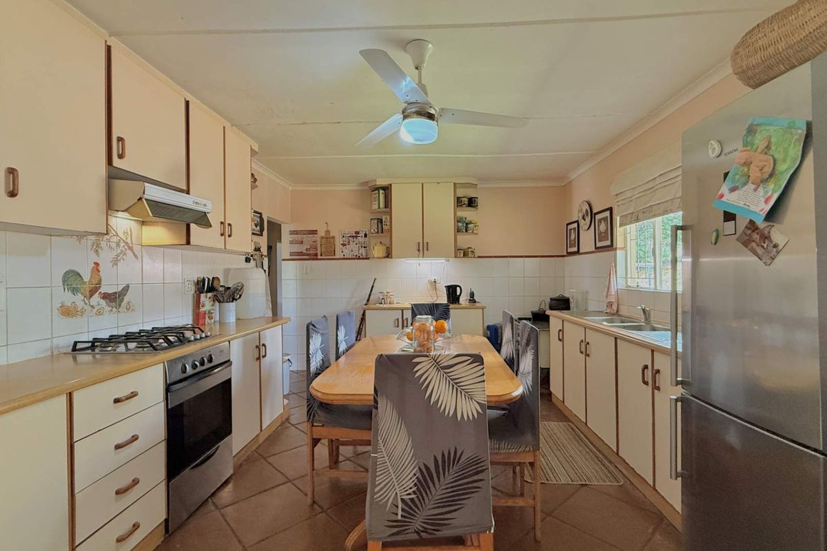 A functional kitchen featuring built-in cabinetry, a gas hob with extractor, double sink, and tiled flooring, offering a practical layout for daily meal preparation.