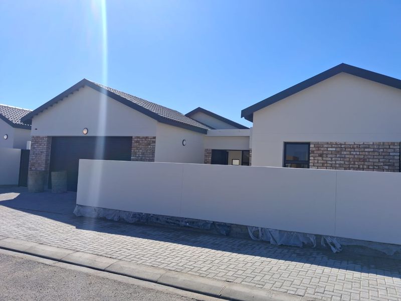 Modern single-story residential property featuring a tiled roof, brick and plaster facade, and a paved driveway with a secure boundary wall.