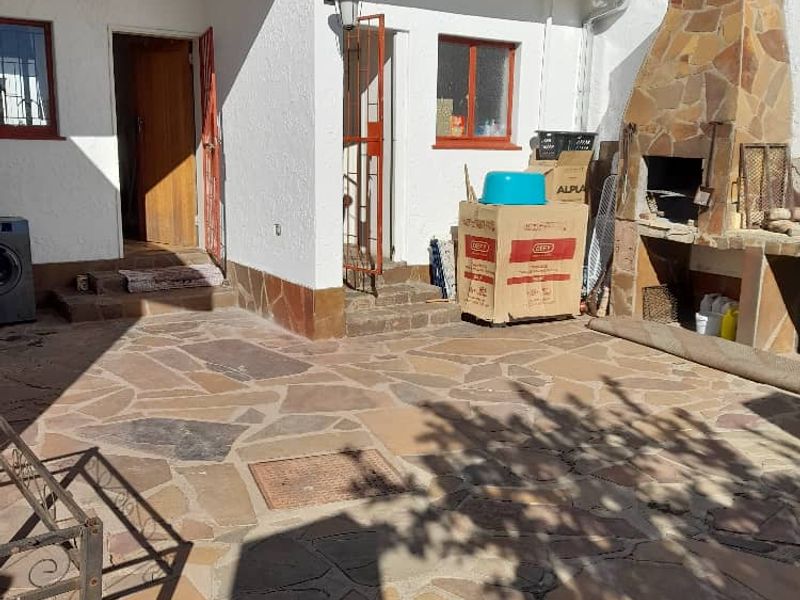 Outdoor patio area featuring flagstone paving and a built-in stone-clad braai, providing a functional space for outdoor entertaining.