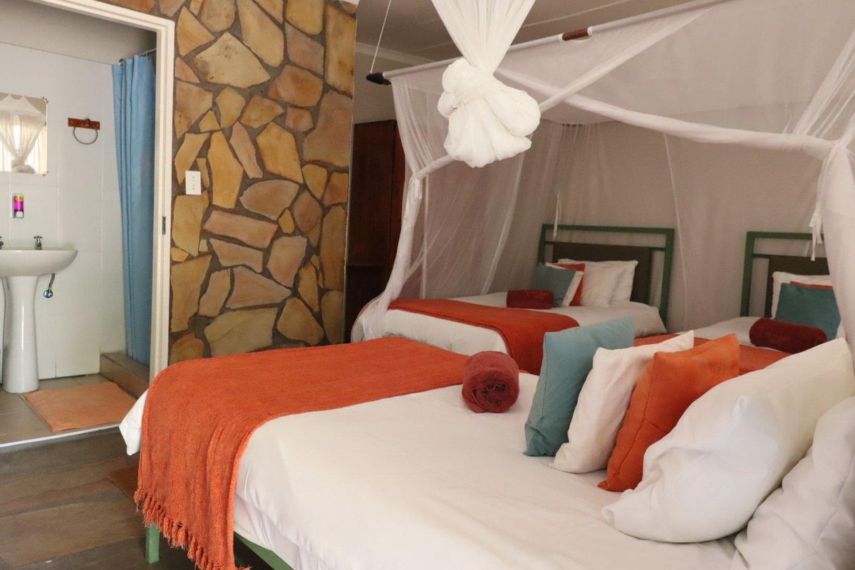 A bedroom featuring a rustic stone feature wall and an en-suite bathroom with a pedestal basin.
