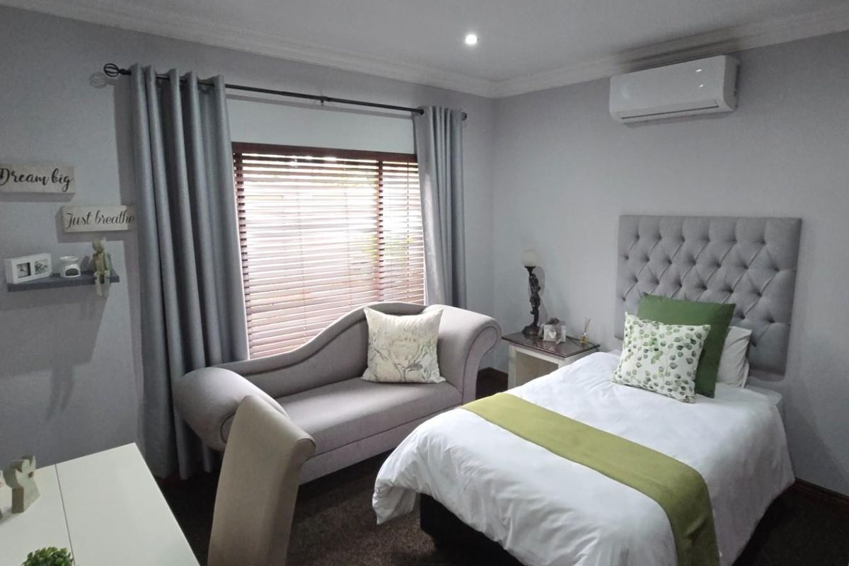 A well-maintained bedroom featuring carpeted flooring, a split-system air conditioner, and timber venetian blinds, offering a comfortable and functional living space.