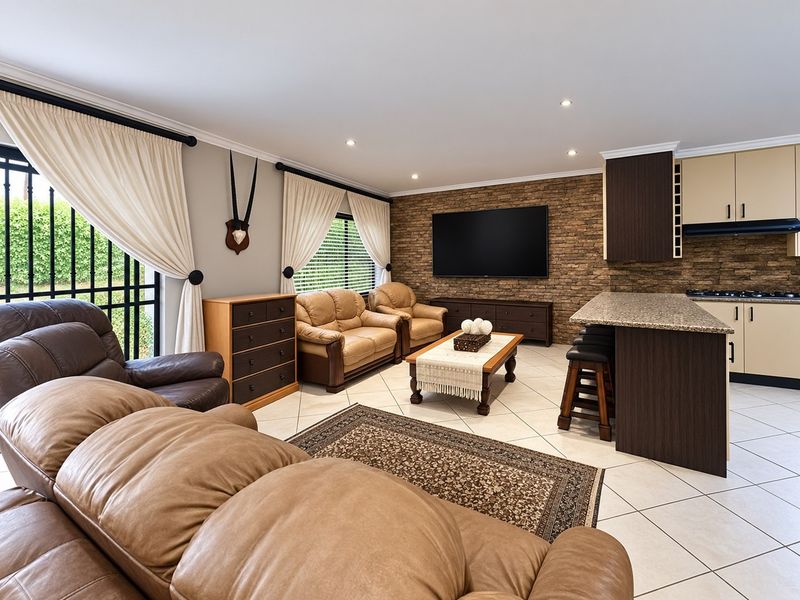 Spacious open-plan living area featuring a stone veneer feature wall, modern kitchen with granite countertops, and tiled flooring throughout.