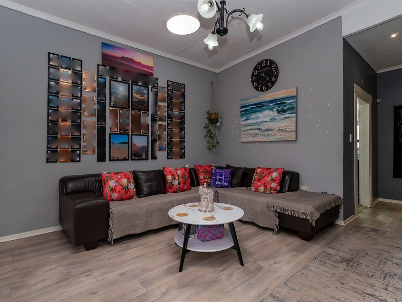 A comfortable living room featuring light-toned laminate flooring and neutral grey walls, providing a versatile space for relaxation and family gatherings.