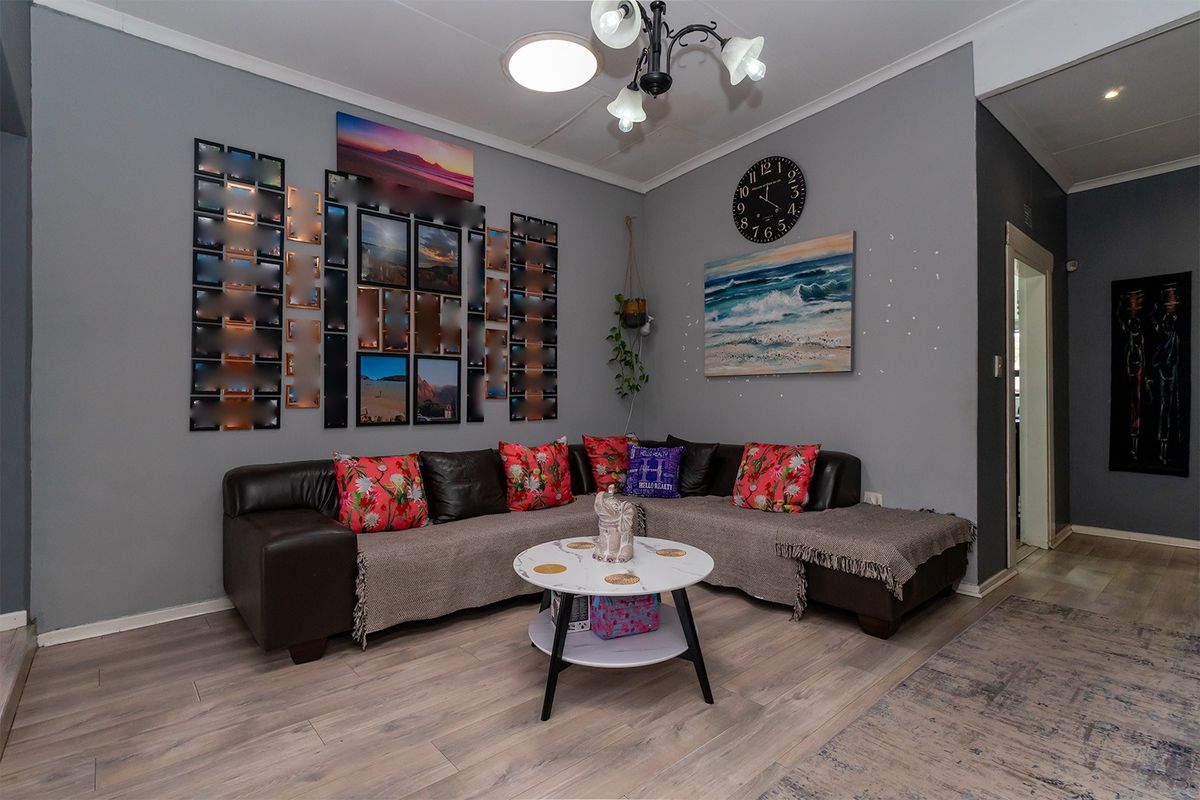 A comfortable living room featuring light-toned laminate flooring and neutral grey walls, providing a versatile space for relaxation and family gatherings.