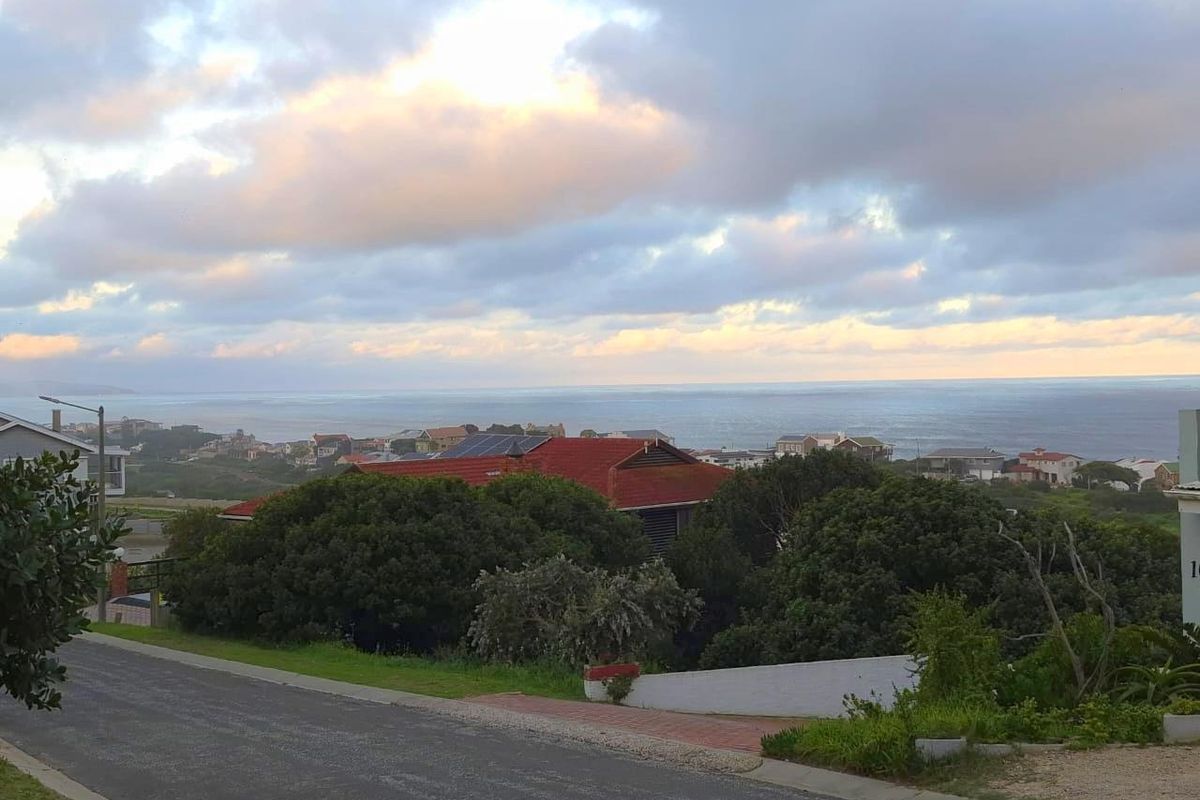 A scenic elevated view overlooking a coastal residential neighbourhood with ocean vistas under a cloudy sky.