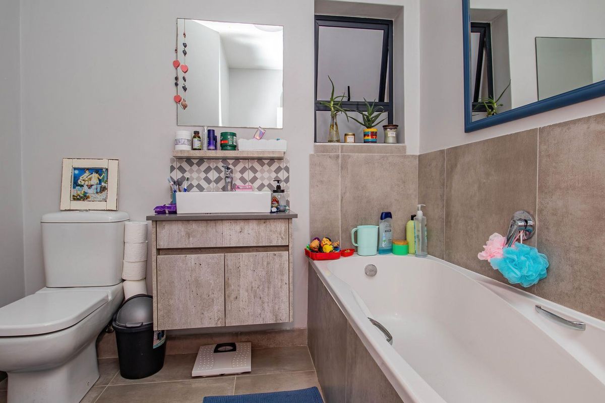 A functional bathroom featuring a modern vanity with a vessel sink, a bathtub with tiled surround, and a standard toilet.