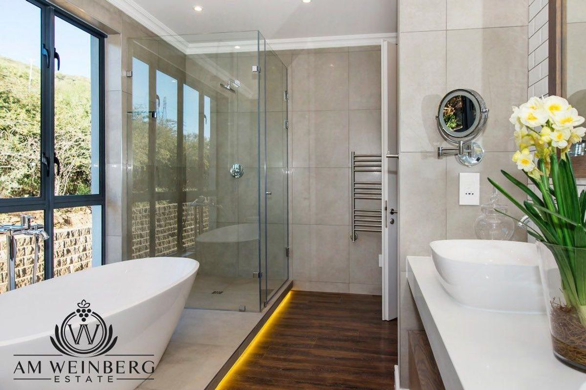 Modern bathroom featuring a freestanding bathtub, glass-enclosed walk-in shower, vessel sink vanity, and heated towel rail with contemporary tile finishes.