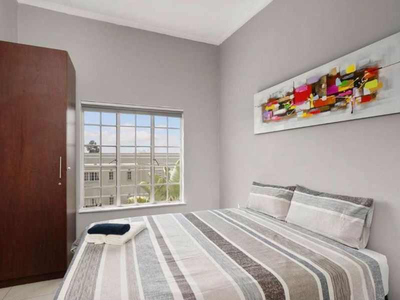A well-maintained bedroom featuring a built-in wardrobe and a window with security bars, offering a clean and functional living space.