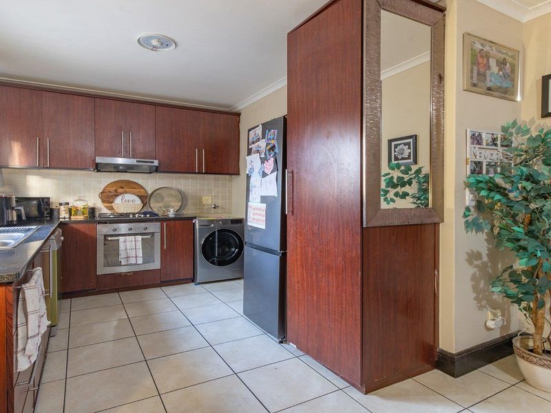 A functional kitchen featuring dark wood-look cabinetry, granite countertops, integrated stainless steel appliances, and tiled flooring with a practical layout.