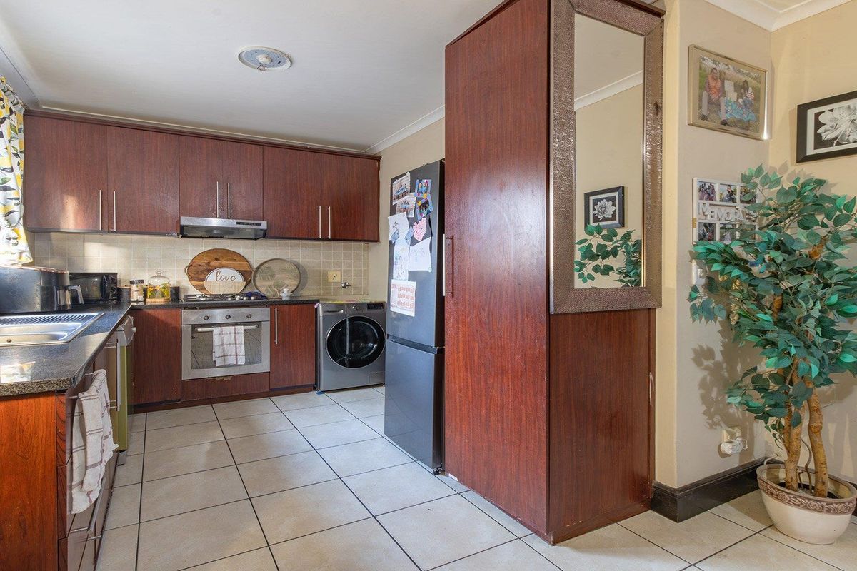 A functional kitchen featuring dark wood-look cabinetry, granite countertops, integrated stainless steel appliances, and tiled flooring with a practical layout.