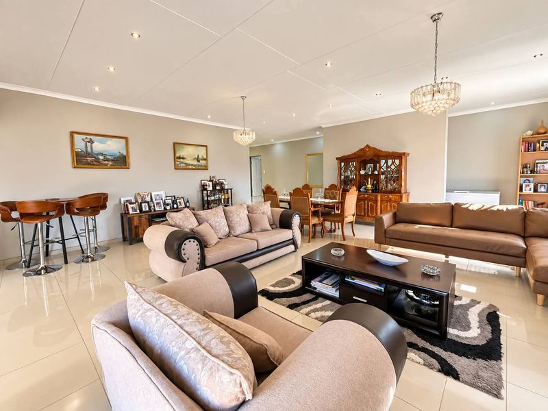 Spacious open-plan living and dining area featuring polished tiled flooring, modern recessed downlighting, and elegant crystal chandeliers throughout the expansive interior space.