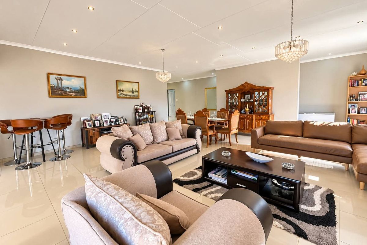 Spacious open-plan living and dining area featuring polished tiled flooring, modern recessed downlighting, and elegant crystal chandeliers throughout the expansive interior space.