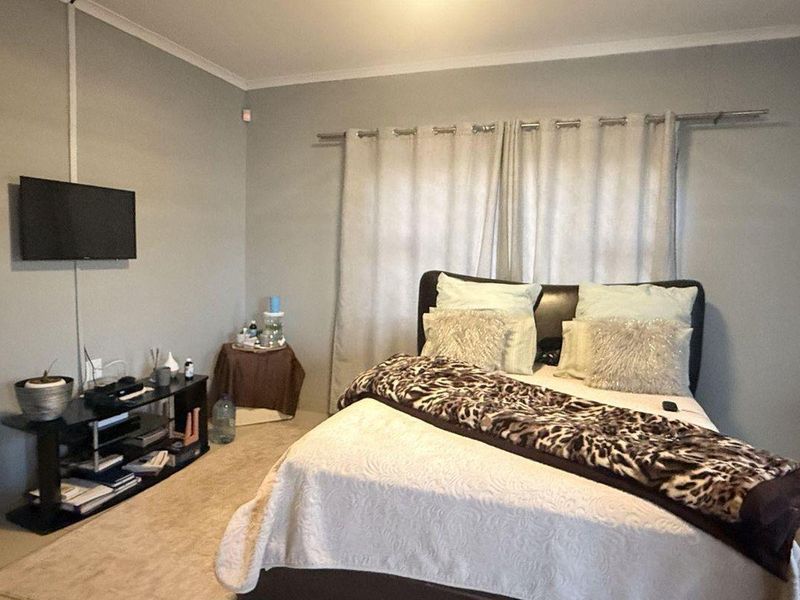A standard bedroom featuring neutral wall paint, carpeted flooring, and a curtain rod installed above the window area.