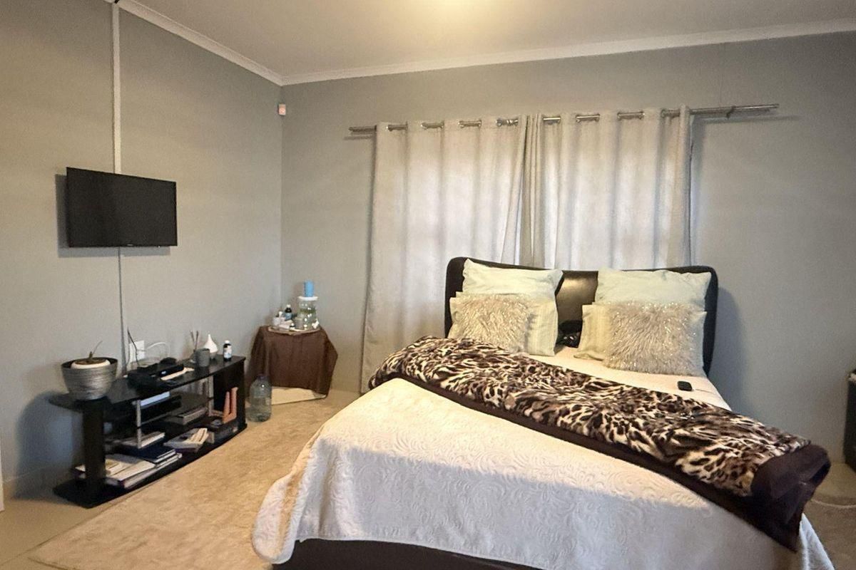 A standard bedroom featuring neutral wall paint, carpeted flooring, and a curtain rod installed above the window area.