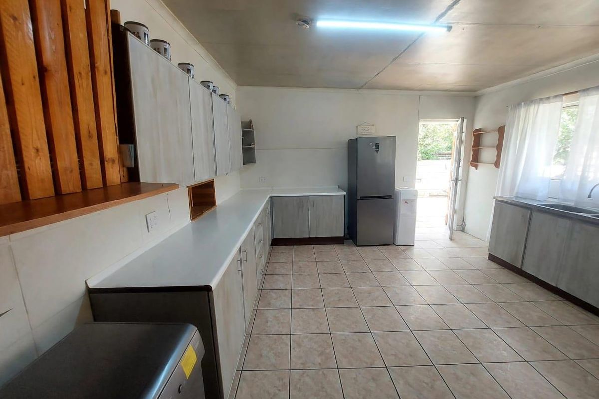 A functional kitchen featuring built-in cabinetry, laminate countertops, and ceramic floor tiles, with direct access to the exterior.