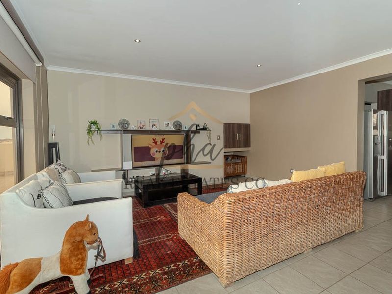 Spacious living room featuring neutral walls, tiled flooring, recessed lighting, and a built-in shelving unit, with direct access to an outdoor area.