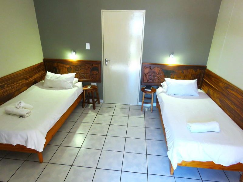 A bedroom featuring ceramic floor tiles, carved wooden headboards, and wall-mounted reading lights.