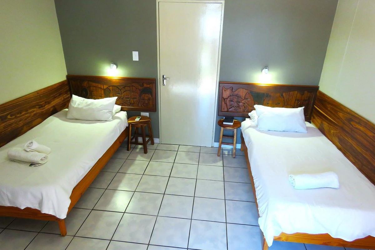 A bedroom featuring ceramic floor tiles, carved wooden headboards, and wall-mounted reading lights.