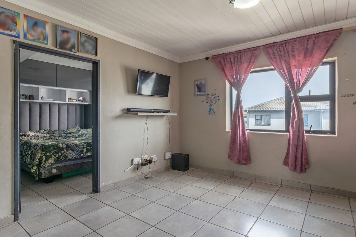 A living room featuring tiled flooring and a tongue and groove ceiling, with a view into the adjacent bedroom.