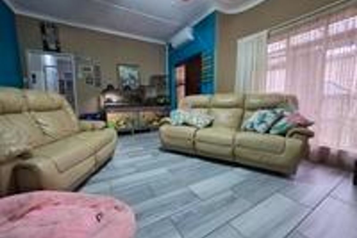 A living room featuring tiled flooring, a wall-mounted air conditioning unit, and decorative ceiling molding.
