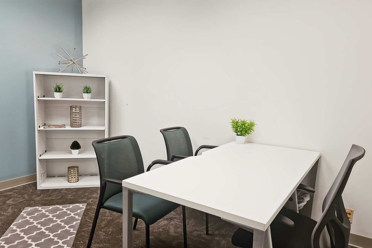 A functional office space featuring neutral wall tones, carpeted flooring, and an integrated electrical outlet, suitable for a professional work environment.