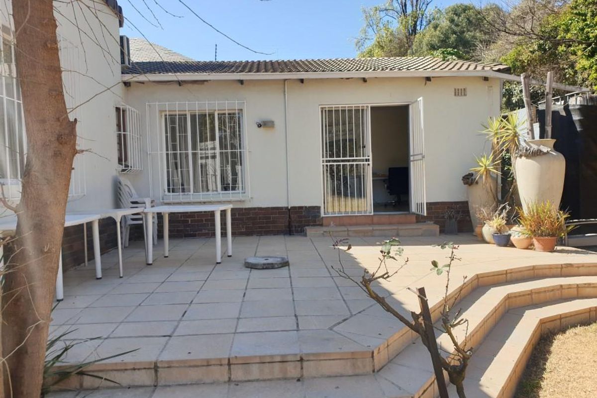 Rear exterior view of the office property featuring a paved patio area with stepped access and security bars on windows and doors.