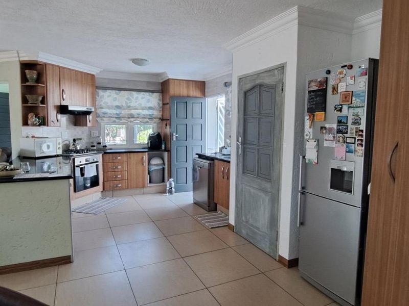 Open-plan kitchen and living area featuring tiled flooring, wooden cabinetry, built-in oven, and gas hob, providing a functional and connected living space.