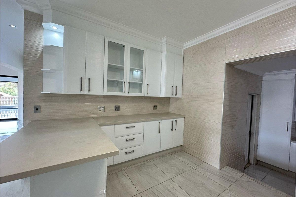A modern kitchen featuring white cabinetry, stone-look countertops, tiled walls, and floor tiles, offering a clean and functional workspace.