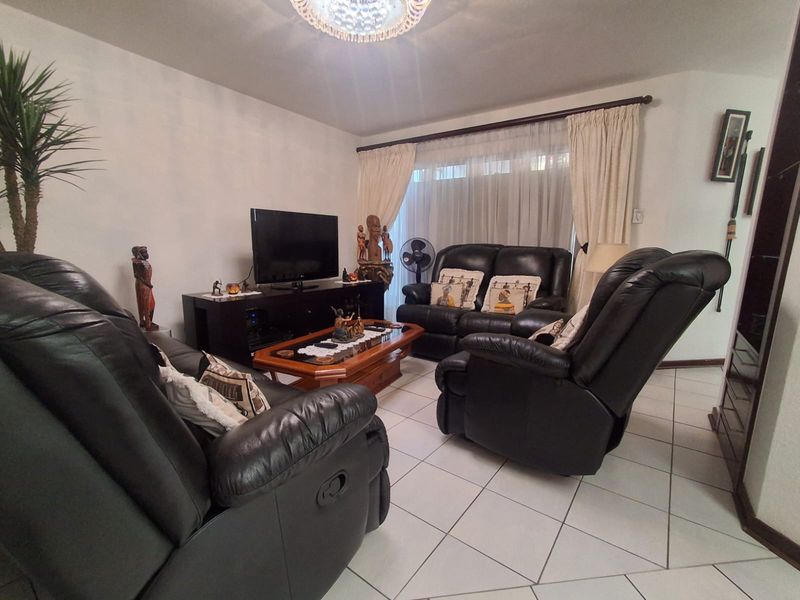 A comfortable living room featuring tiled flooring and large windows with curtain treatments, providing a functional and well-lit space for relaxation.